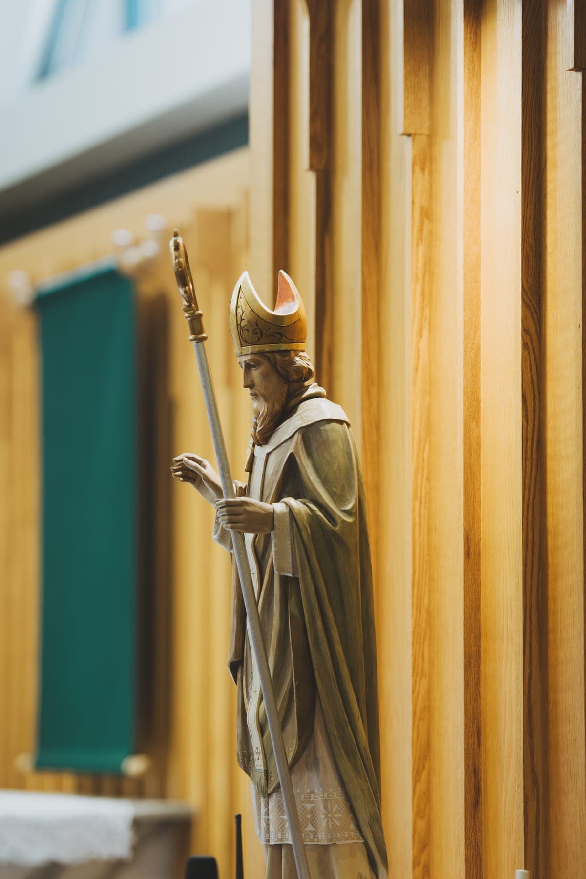 The statue of St. Patrick standing beside the green seasonal banner in the sanctuary